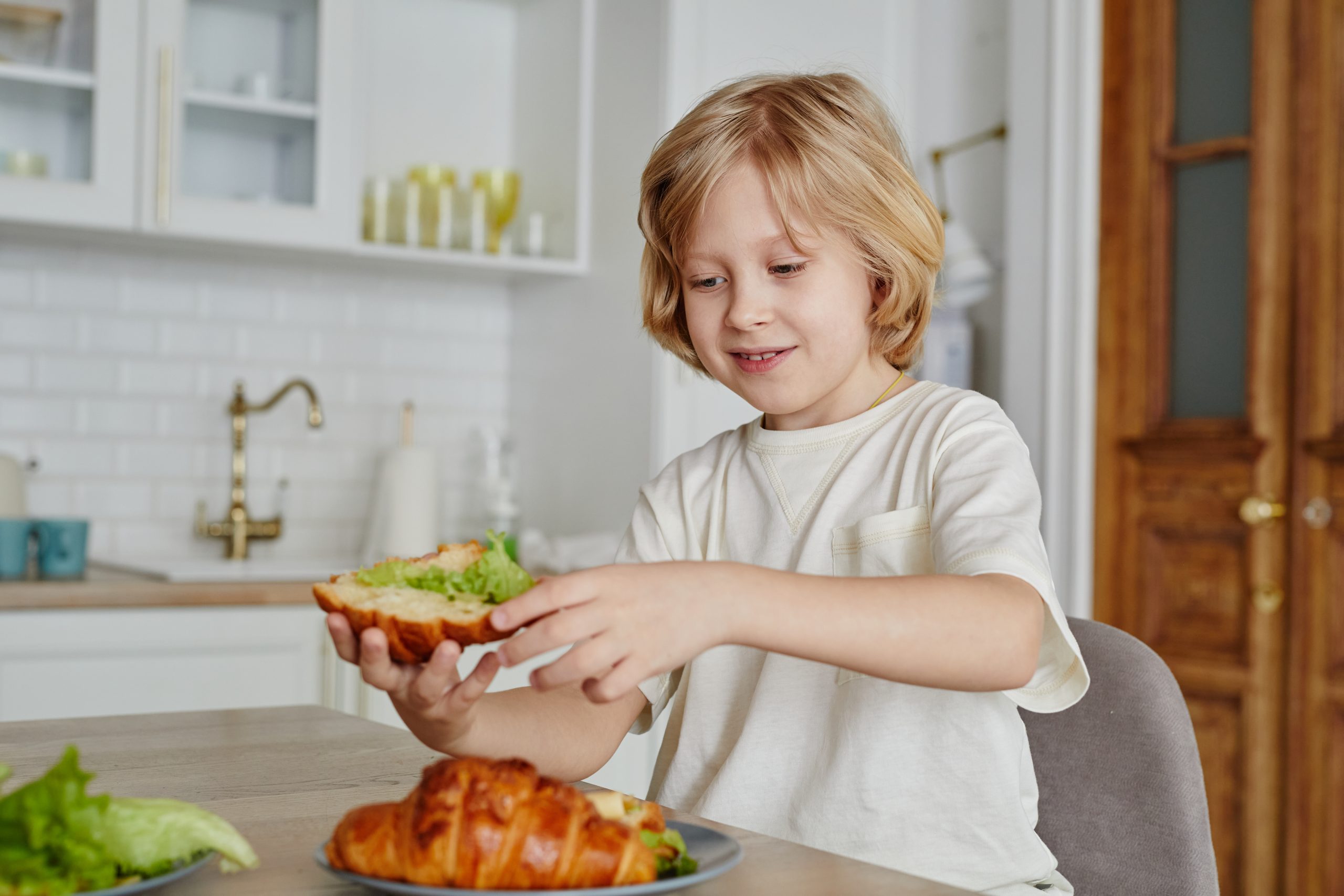 Smiling Boy Eating Sandwich at Home